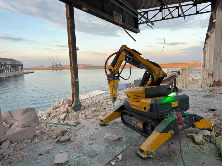Robot BROKK au brise-roche démolissant un hangar sur le port de Marseille, en bord de quai